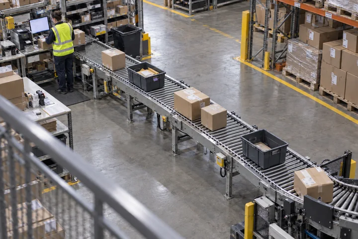 Worker sorting cartons on a warehouse conveyor